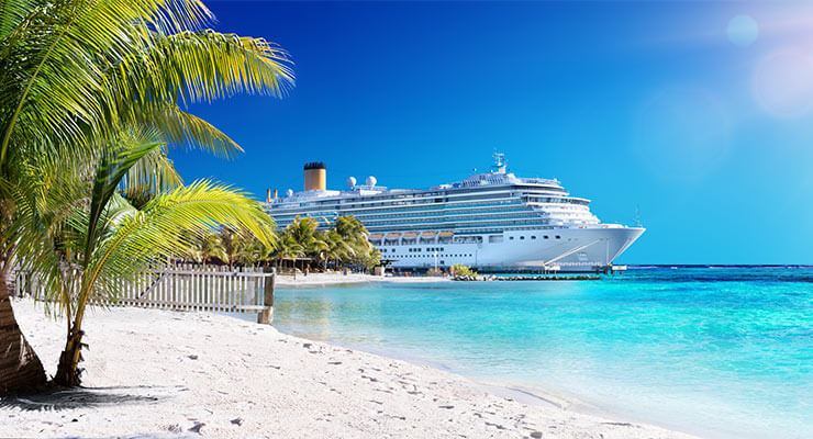 An ocean liner mooring at an exotic island, overlooking palm treees, white sand, and blue sea, a popular choice for wedding anniversary holidays.