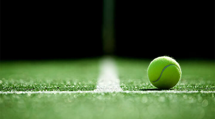 A close up view of a tennis ball on the border lines of a tennis court.