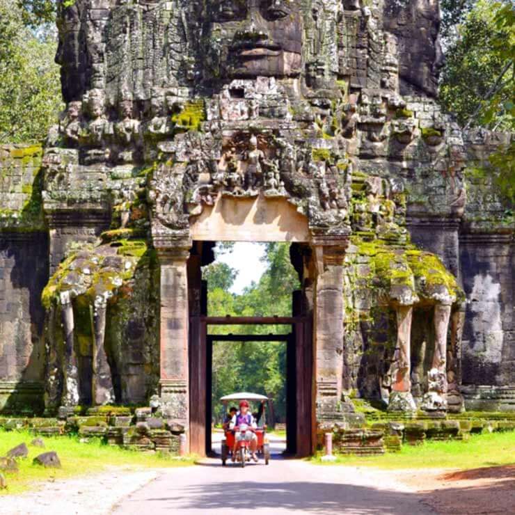 A traditional cart car driving through temple gates in cambodia.