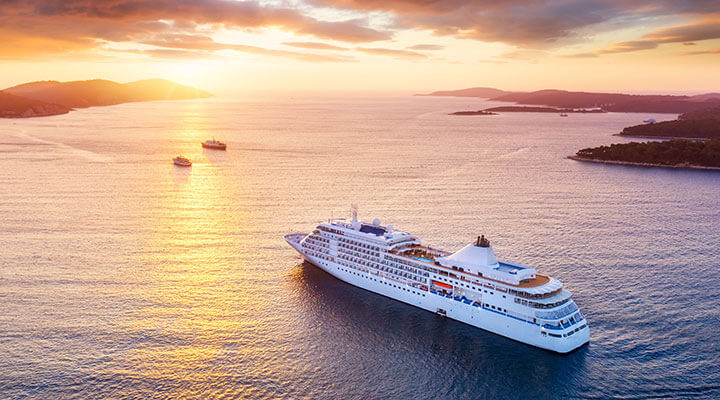 A large ocean liner cruising through the ocean into the sunset on a cruise and stay holiday.