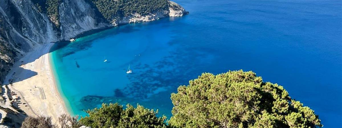 Stunning view of the bay on holiday in Kefalonia, with aqua blue waters lapping on a sandy beach by the cliffs.