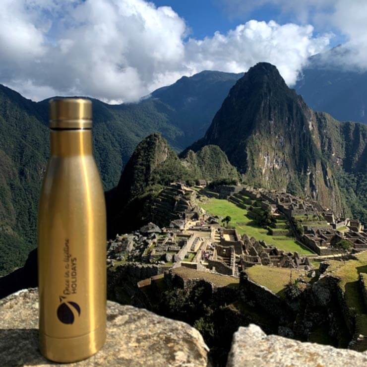 A once in a liftime drink bottle sitting on a wall overlooking the famous inca trail of machu picchu.