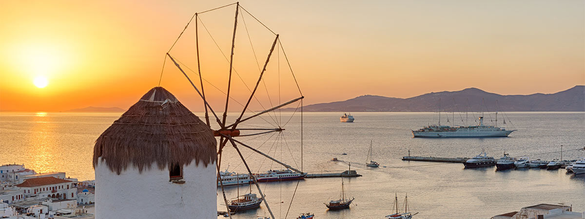 The world famous views of historic windmills in the greek islands, framed by the sunset.