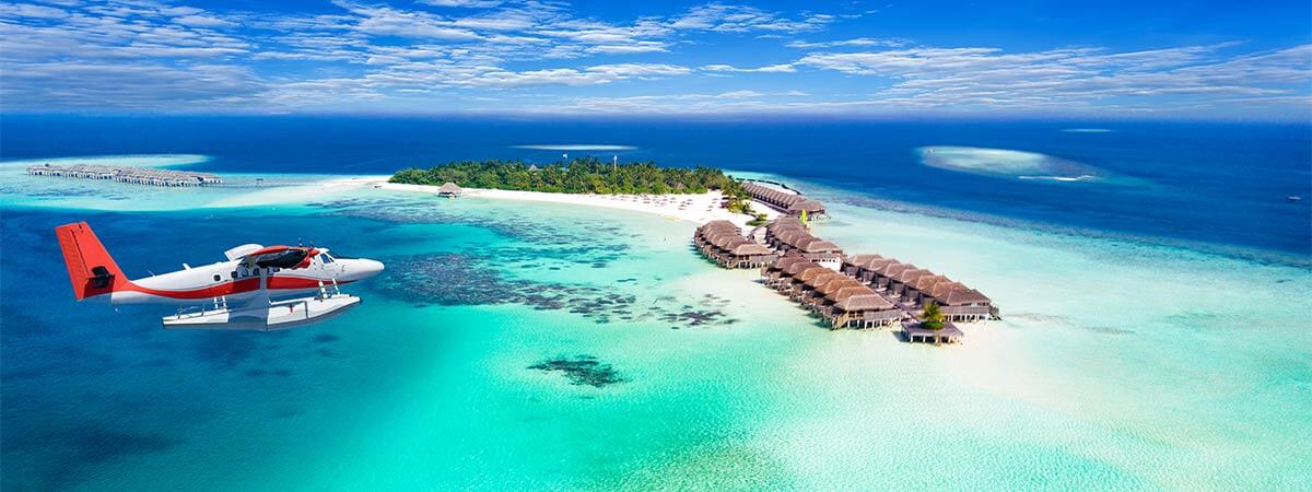 Aerial view of the maldives holiday villas with a light plane soaring above.