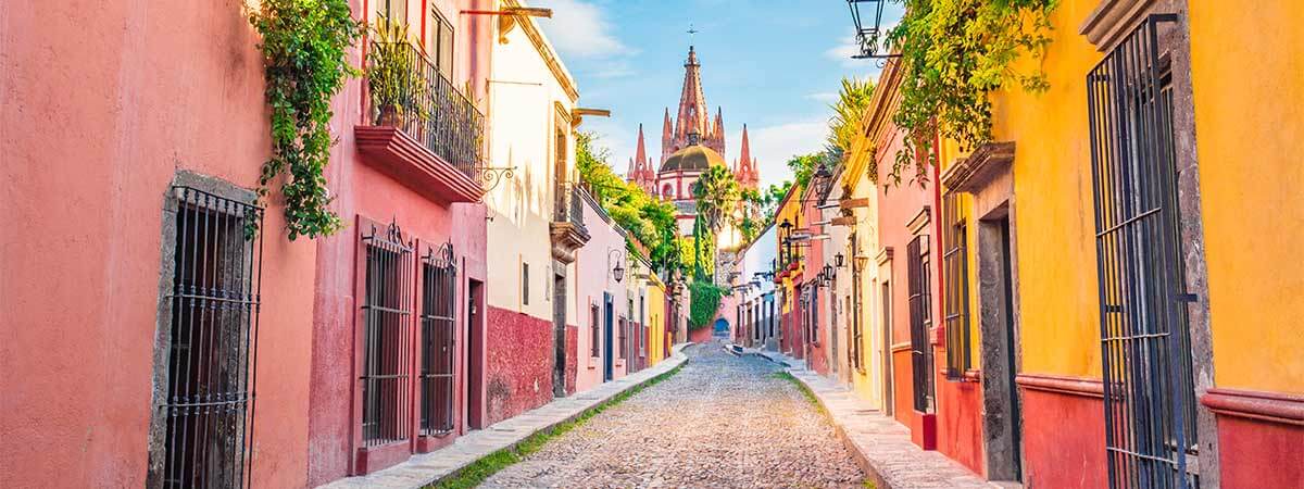 The beautiful colours of mexican streets, with red, yellow and orange walls, lined with flowes.