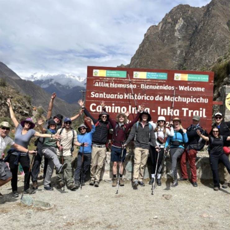 A group of tourists celebrating at the top of machu picchue after completing the inca trail hike in peru.
