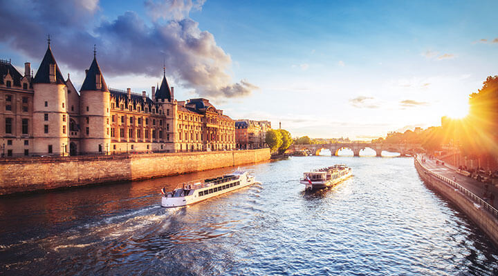 The sun setting over a riverboat on a river cruise holiday making its way down the Seine through Paris.