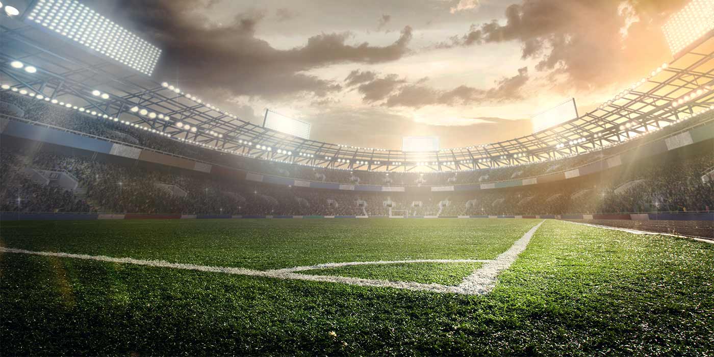 A huge sports stadium, lit up with tower lights, with crowds cheering on the team.