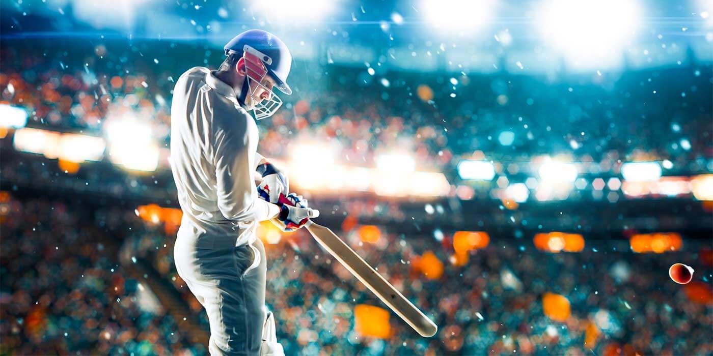 A cricket player hitting the ball with his bat at a night game, with crowds on sporting holidays cheering.