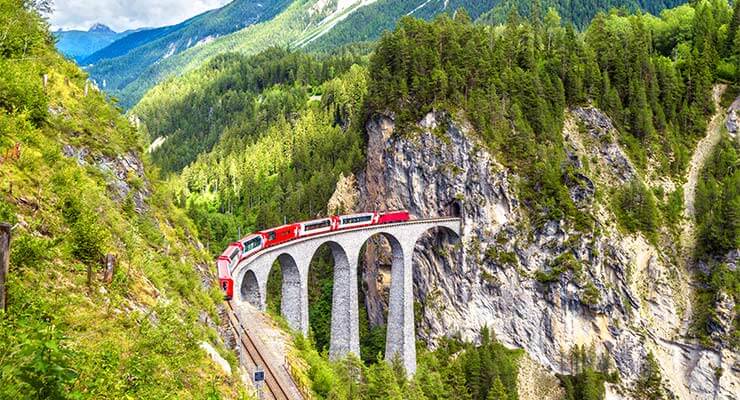 The iconic Glacier express running over the Landwasser Viaduct in Switzerland, on luxury swiss rail holidays.