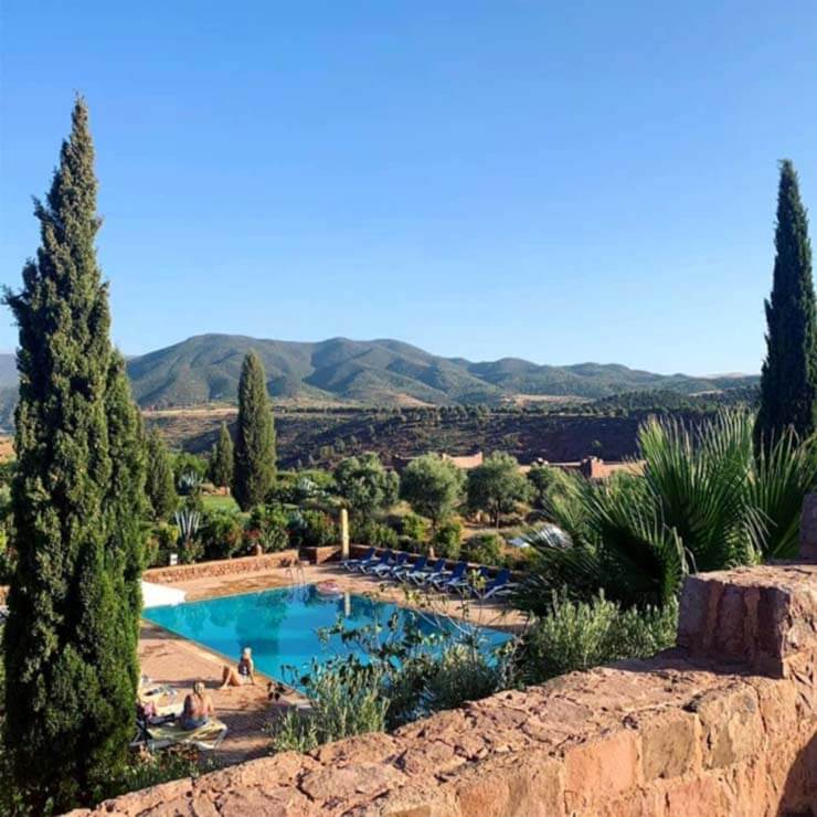 The view of the pool at the hotel in Morocco, lined with red stone walls.