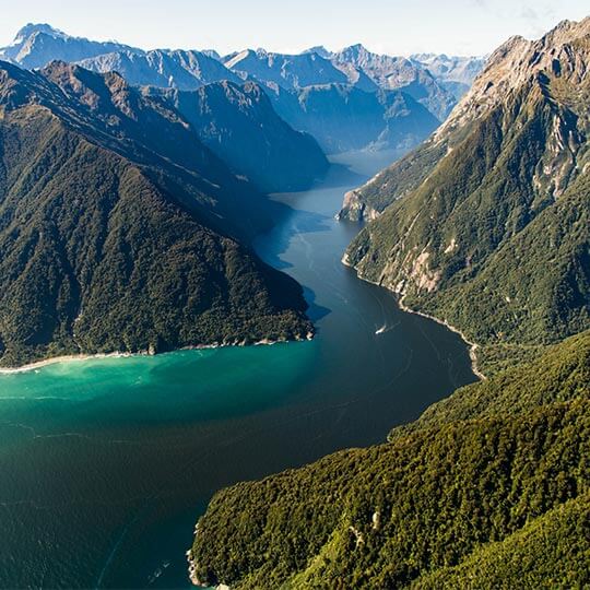 The majestic view of Milford Sound in New Zealand, a river weaving through spectacular mountains.