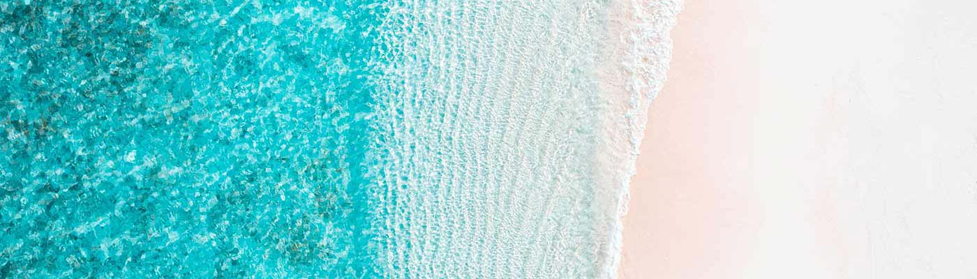 Aerial view of a beautiful beach, with clear blue sea lapping up on white sand.