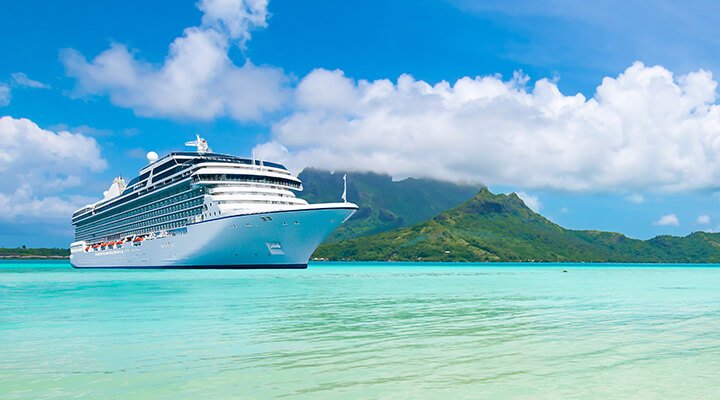 A massive ocean cruise liner moored at a tropical island as part of a world cruise.