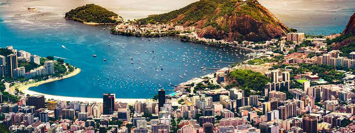 The gorgeous city of rio de janeiro, with the city set on the beach, with mountains in the background.