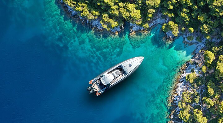 A magnificent yacht moored in the blue waters of a beautiful bay on a private island as part of a luxury cruise holiday.