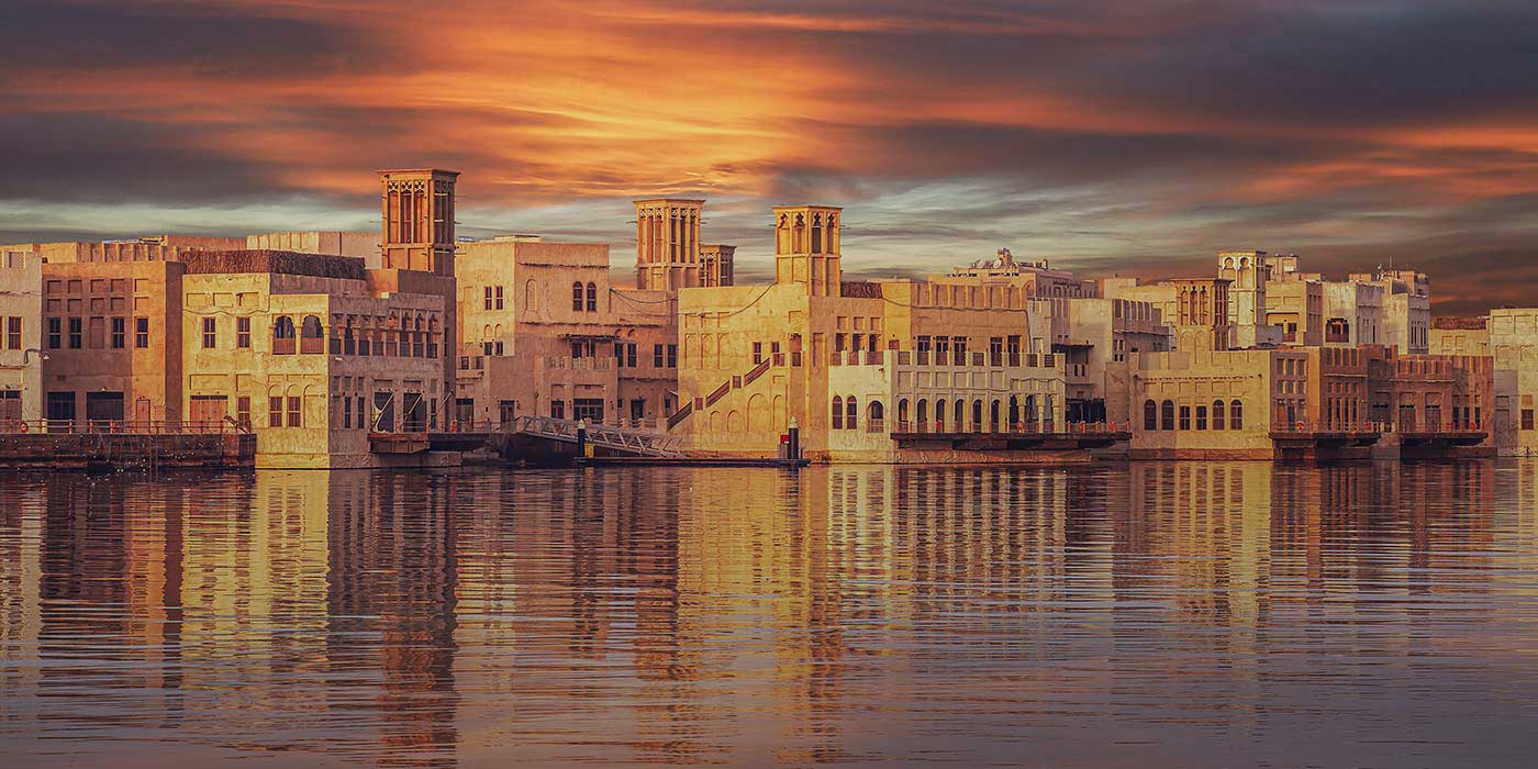 Beautiful pink and orange sunrise over old Dubai city, with the old houses overlooking the canal.