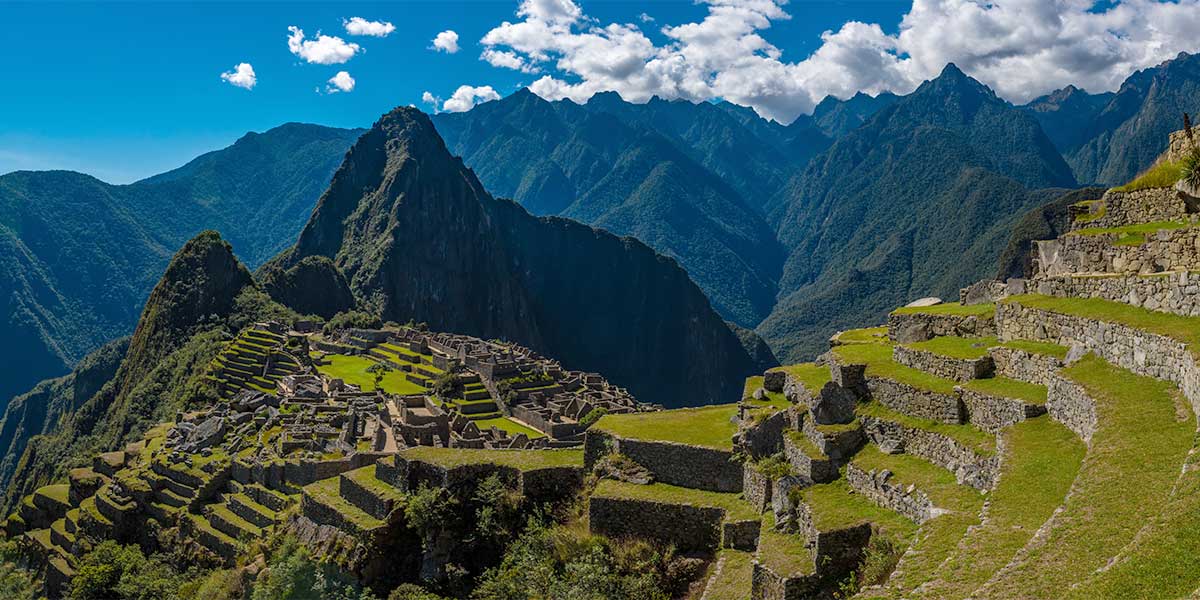 The majestic view from the top of Machu Picchu, with the ancient stone walls and lush green scenery against the backdrop of peruvian mountains.