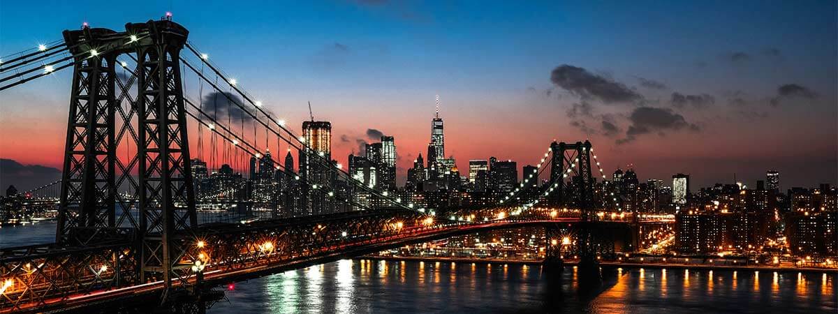 Williamsburg bridge in new york, lit up against the NYC skyline.