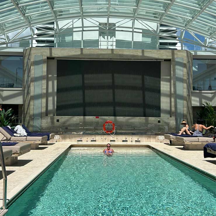 A holidaymaker relaxing in the luxurious pool onboard an explora journey cruise to the caribbean.