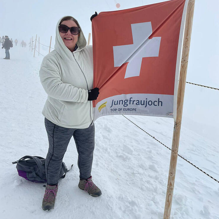 Rachel Baber standing with a flag on the snow at Jungfraujoch, Europe's highest altitude railway station.