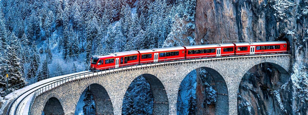 The famous red swiss alps train passing through the Landwasser Viaduct in the winter.
