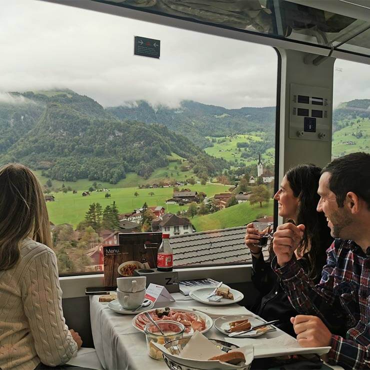 A group of friends on a train journey holiday in switzerland looking out the window at the beautiful scenery.