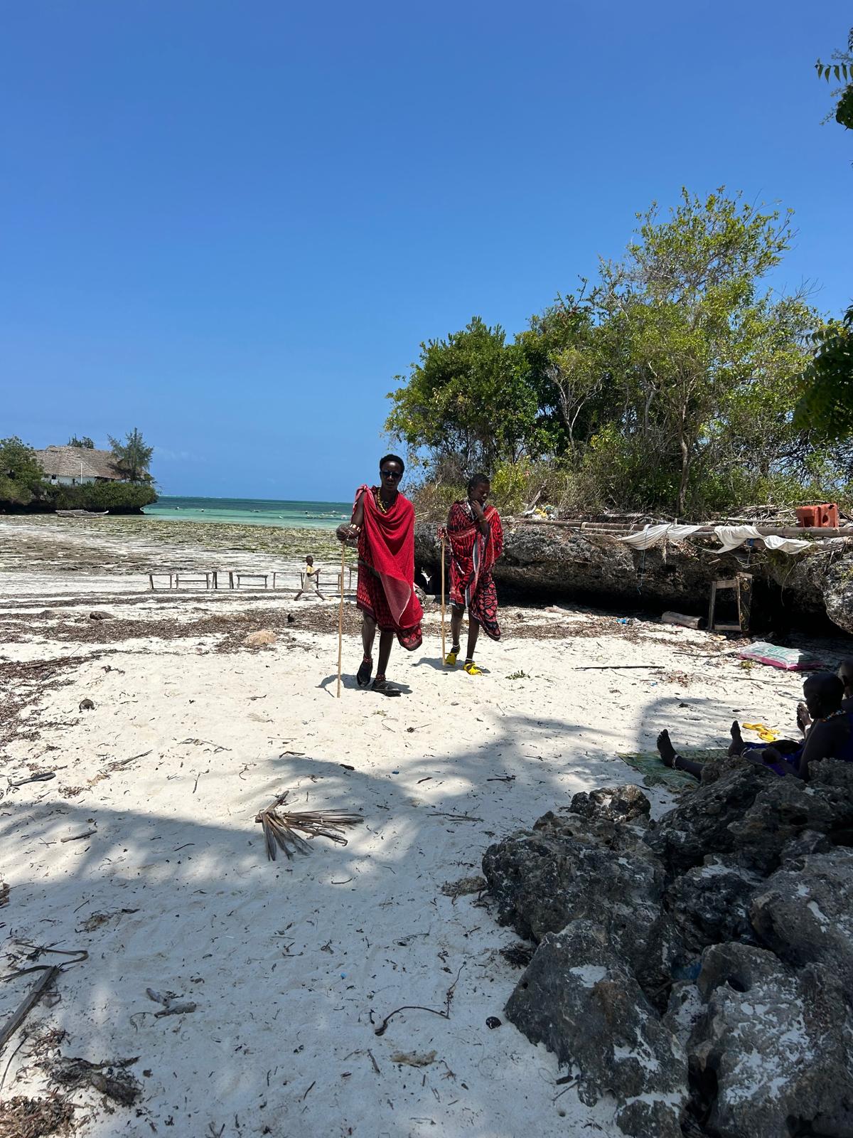 Masai tribesmen on tropical beach with traditional red robes