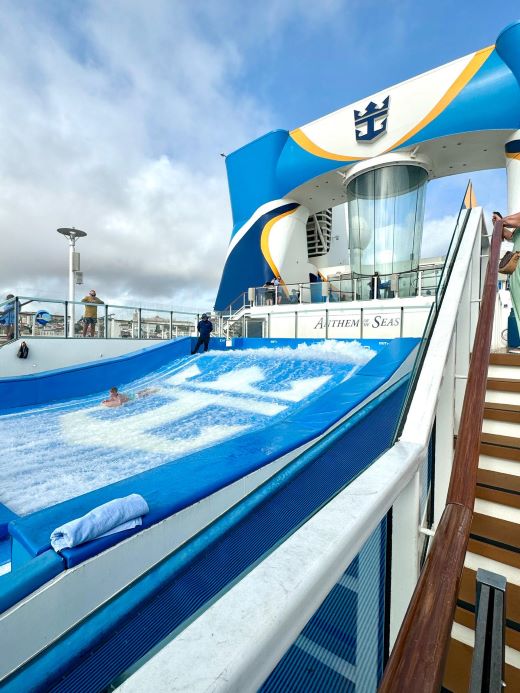FlowRider wave surfing simulator aboard Royal Caribbean's Anthem of the Seas cruise ship with blue sky and cruise deck in background