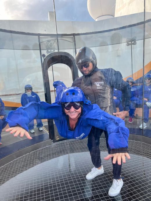 Guest enjoying indoor skydiving experience in RipCord by iFLY simulator aboard Royal Caribbean's Anthem of the Seas with instructor
