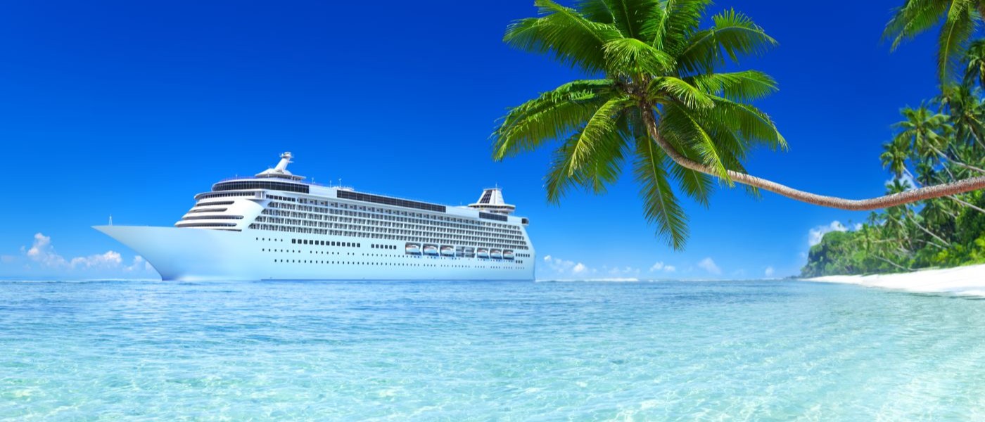 An ocean cruise docked at an exotic island with white sand beaches and palm trees.