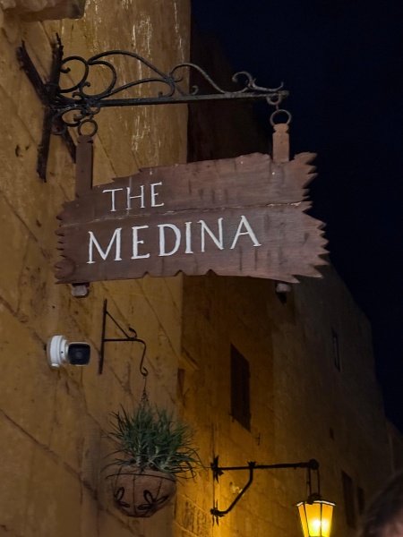 The Medina restaurant sign illuminated at night in Mdina Malta Silent City with golden-stone walls and traditional street lamp creating romantic medieval atmosphere