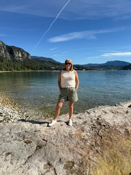 Traveler on Lake Garda pebble beach with crystal-clear waters and dramatic Alpine mountain backdrop showcasing luxury slow travel and tailor-made Italy holidays experience
